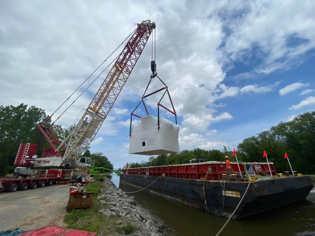 Shoreside crane loading heavy Graham project cargo onto a barge—experience-driven waterfront logistics